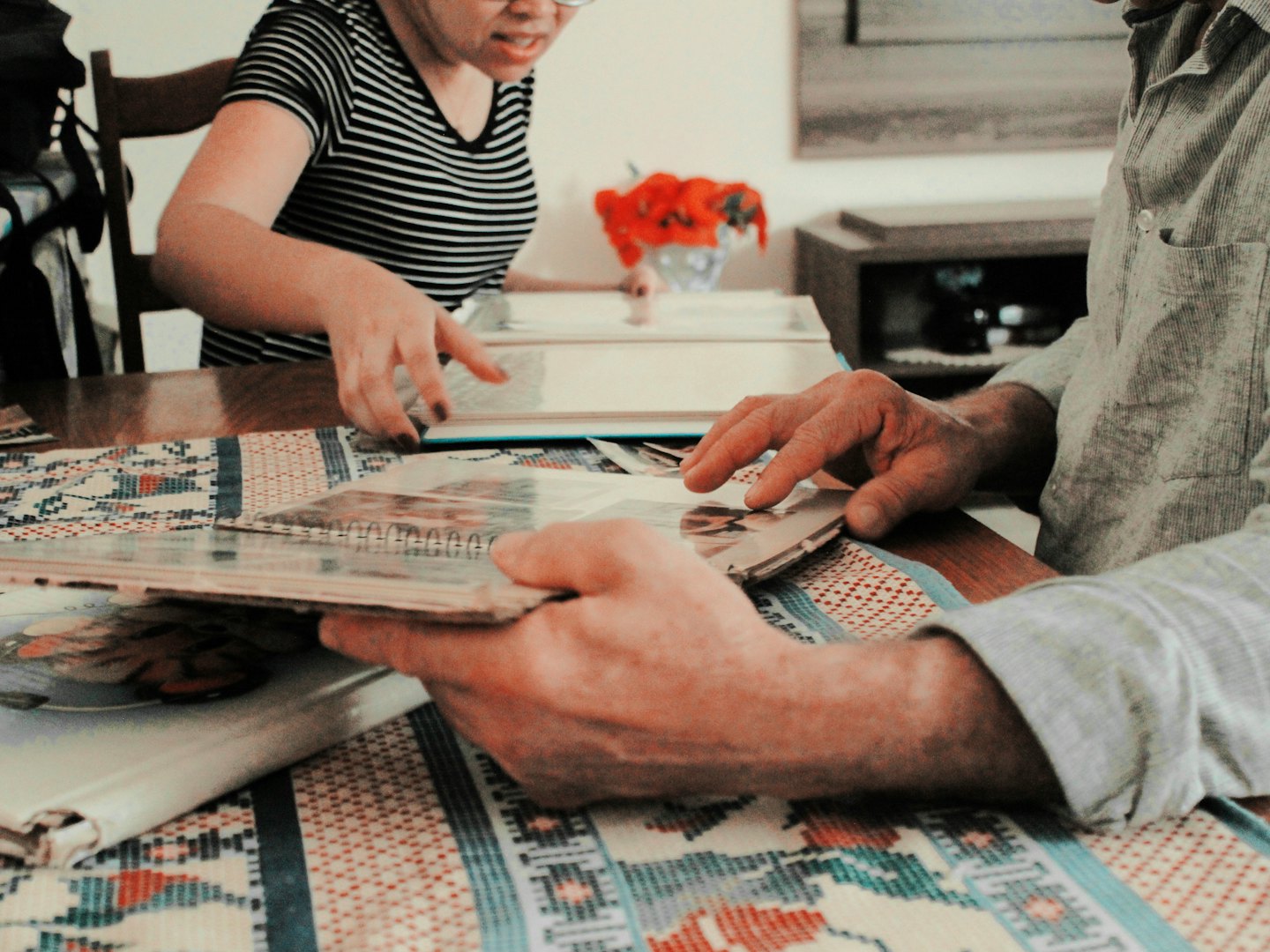 Two people look through old photo albums at a wooden table.
